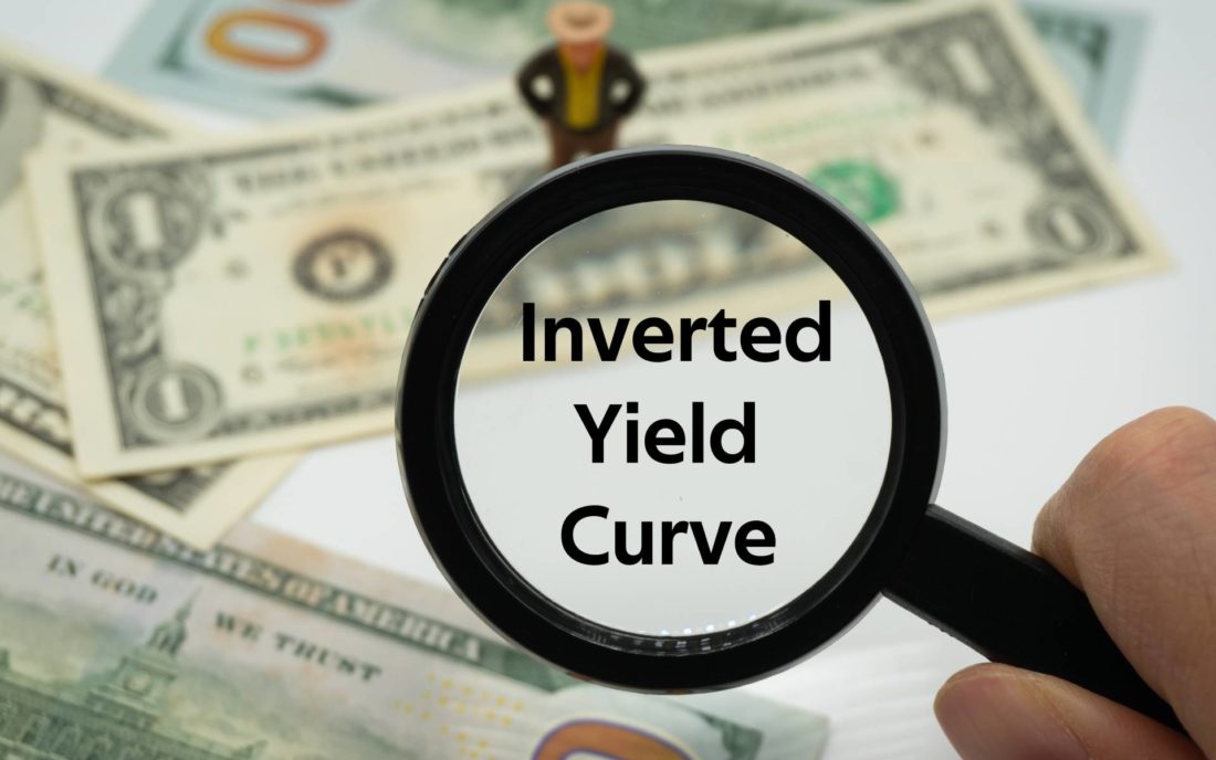Magnifying glass with words "inverted yield curve' written inside it
