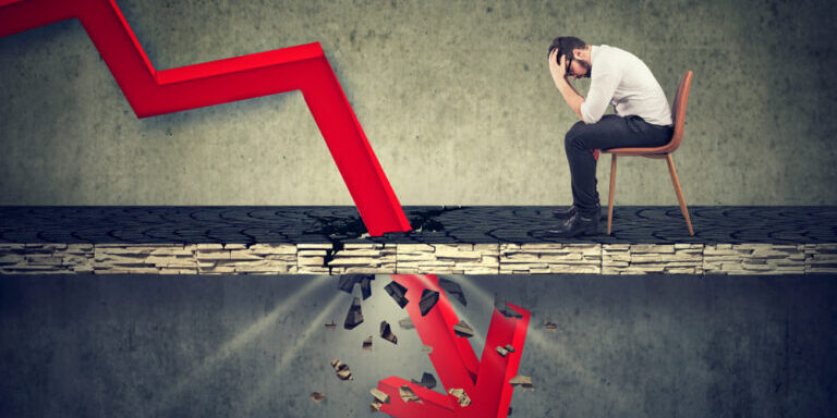 Depressed,Business,Man,Looking,Down,At,The,Falling,Red,Arrow