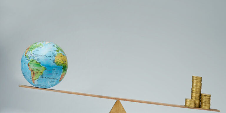 World,Globe,And,Money,Coins,Stack,Balancing,On,A,Seesaw
