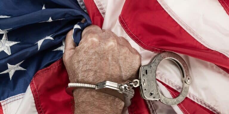A,Man,In,Handcuffs,Grasps,The,American,Flag,In,Frustration A,Man,In,Handcuffs,Grasps,The,American,Flag,In,Frustration