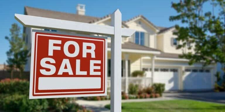 For,Sale,Real,Estate,Sign,In,Front,Of,Beautiful,House.