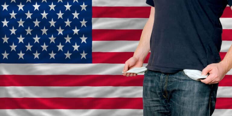 Poor,Man,Showing,Empty,Pockets,In,Front,Of,Us,Flag